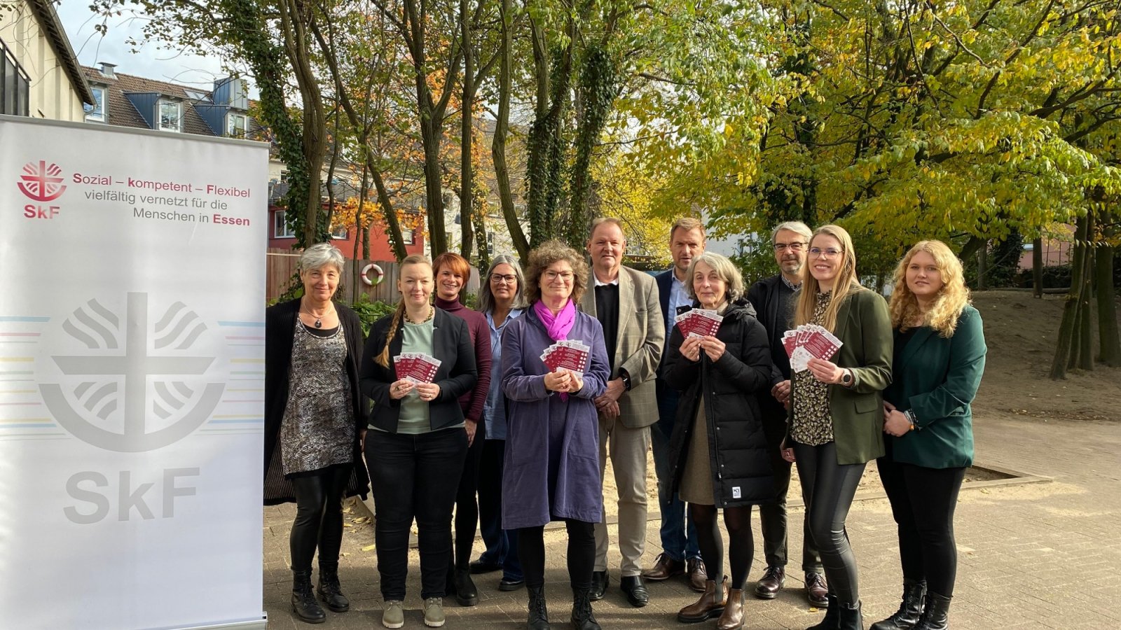 Elf Personen  stehen als Gruppe neben einem Rollup. Sie halten Flyer der Vormundschaften in der Hand. 