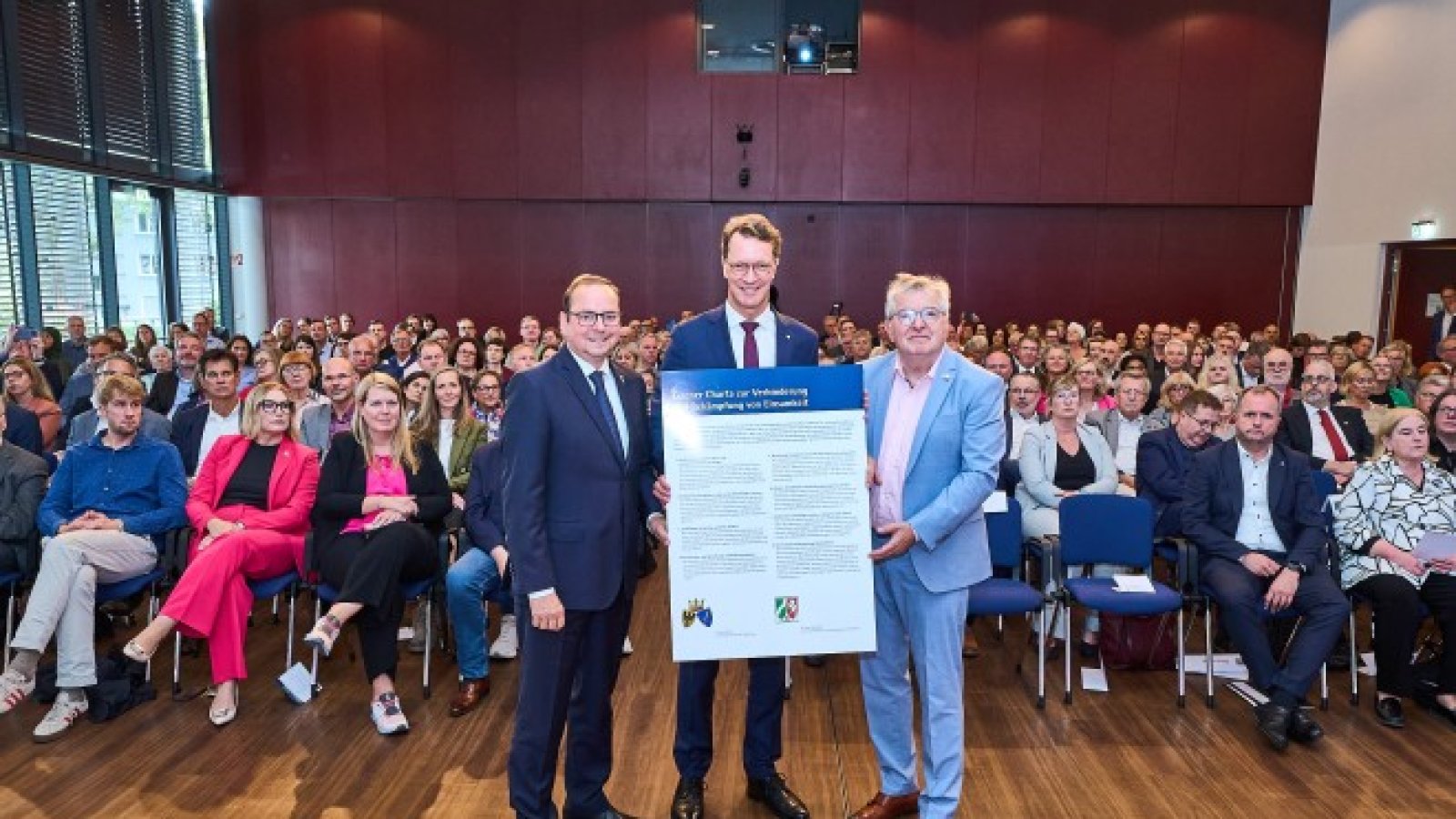 Oberbürgermeister Thomas Kufen , Ministerpräsident Hendrik Wüst und Stadtdirektor Peter renzel vor den Unterstützer:innen mit der Charta in der Hand