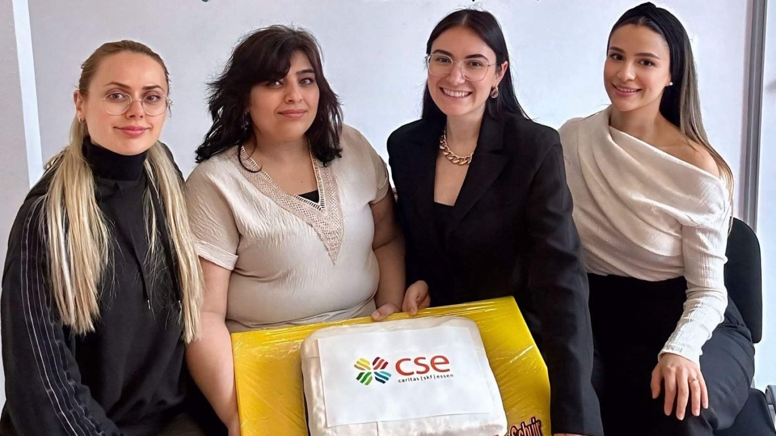 Vier Frauen mit Torte mit Caritas-SkF-Essen Logo drauf