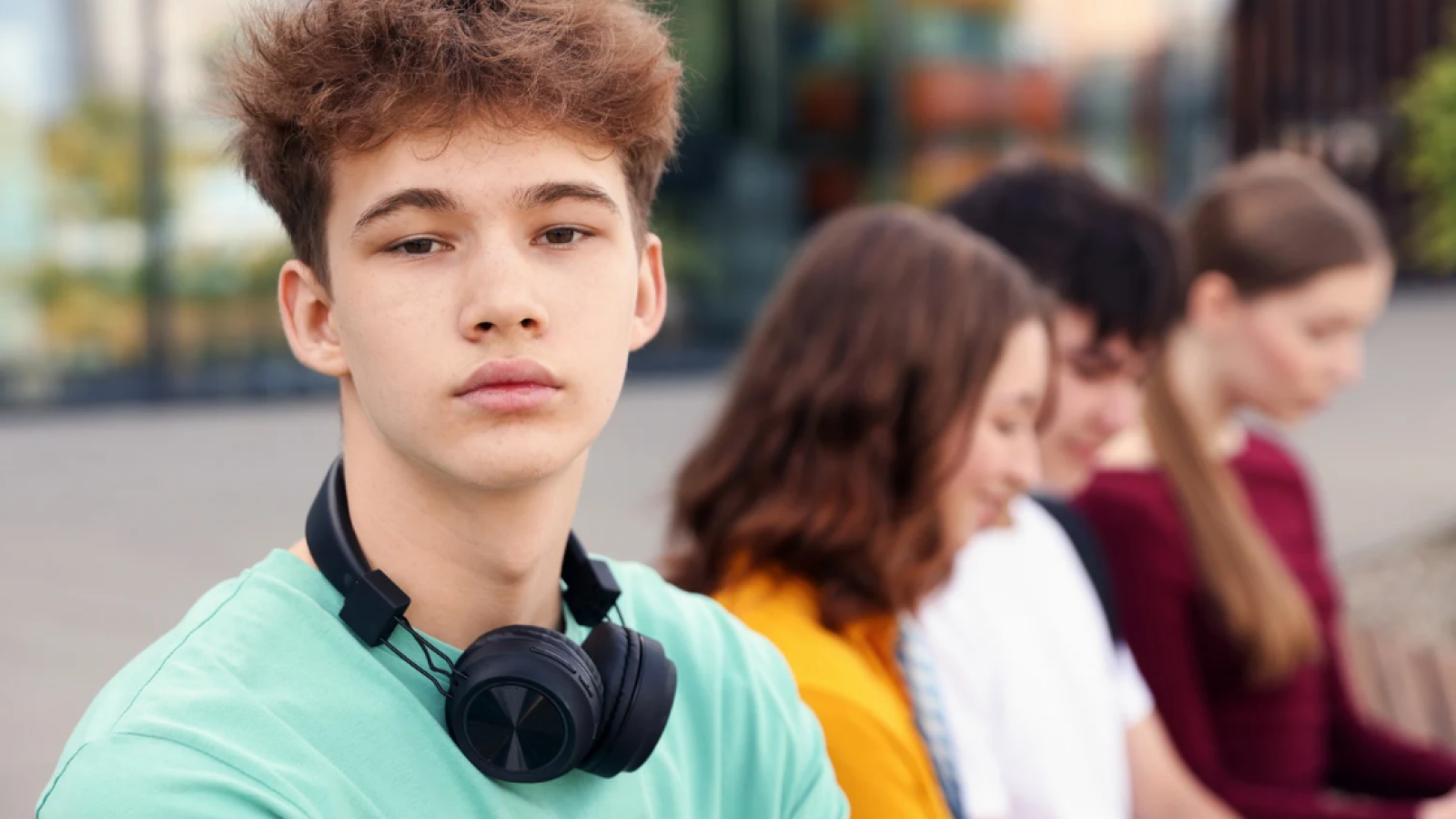 Junge mit Kopfhörern, Gruppe Mädchen im Hintergrund