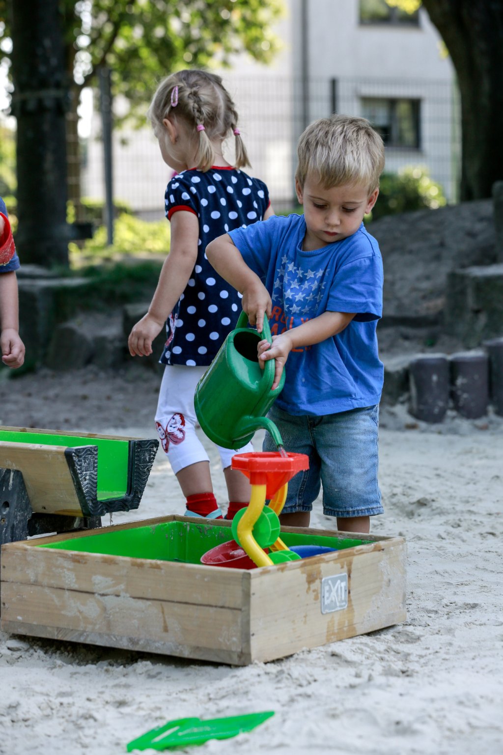 Junge mit Gießkanne beim Spielen im Sand