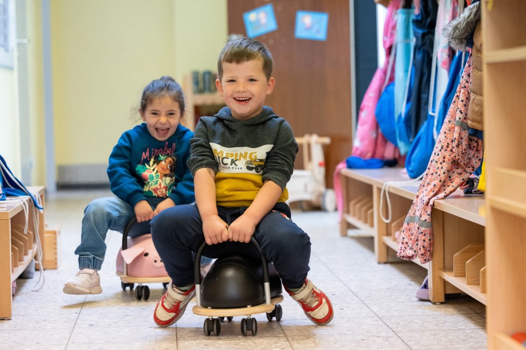Kinder im Flur auf Rutscheautos