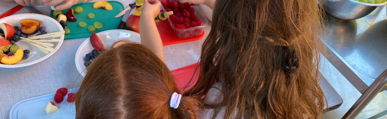 Zwei Mädchen greifen nach Obstspießen
