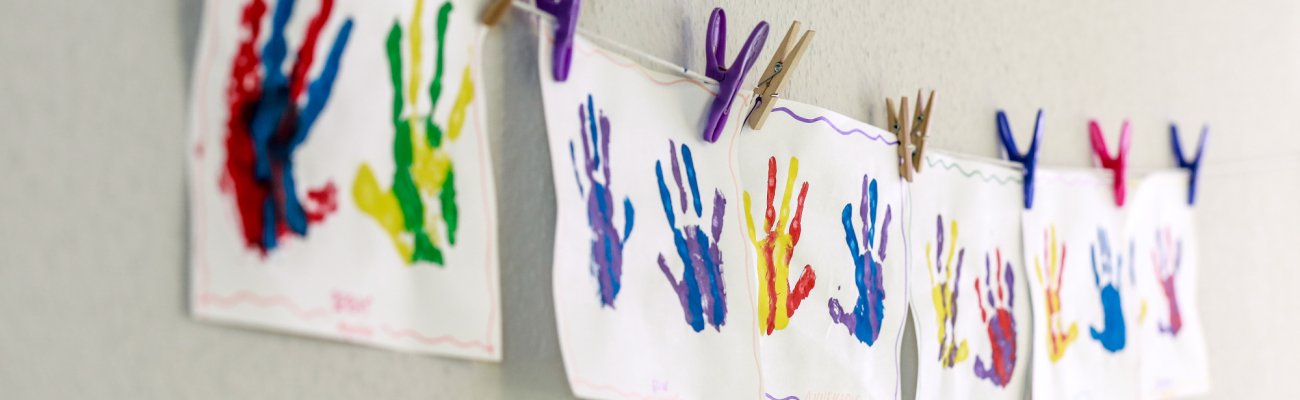 Bilder mit bunten Handabdrücken an Schnur an der Wand